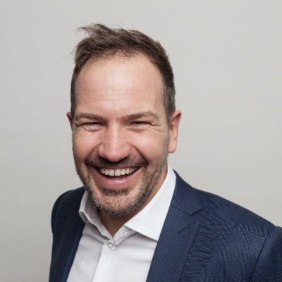 Portrait of Alexander Dierolf smiling in a blue blazer and white shirt