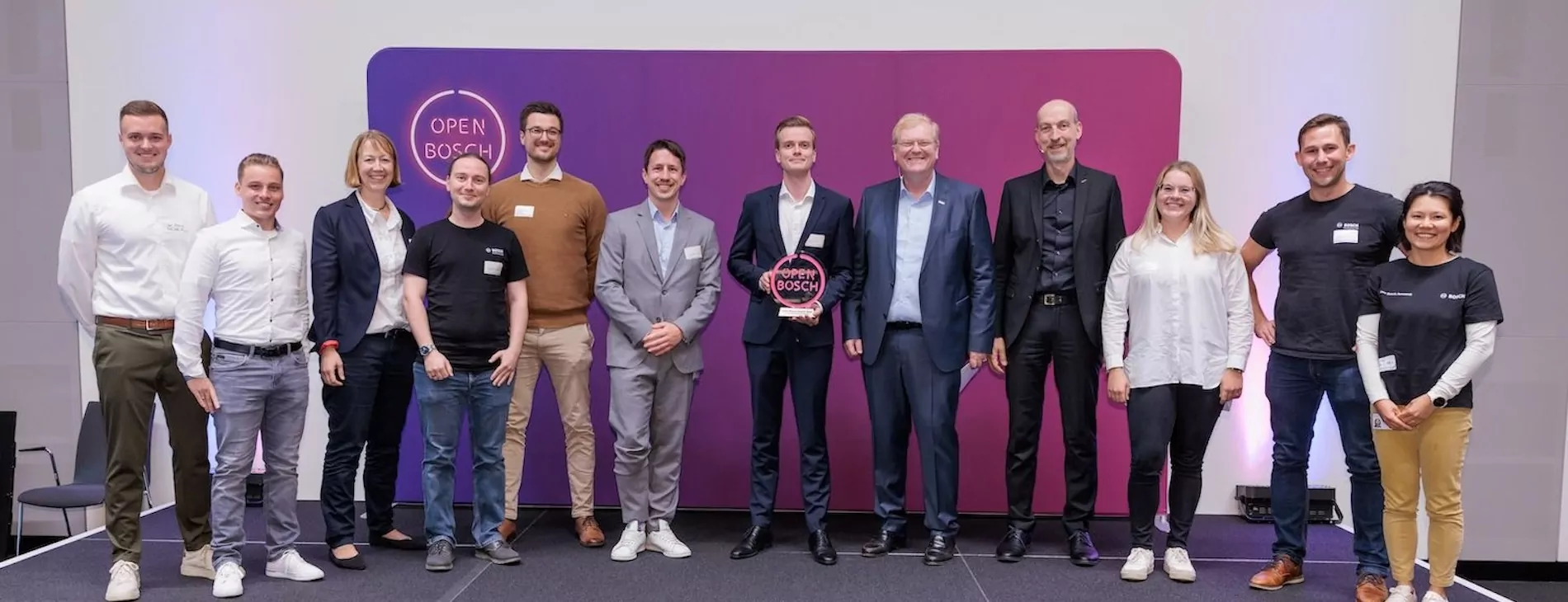 Group photo of award winners at the Open Bosch event holding a trophy on stage